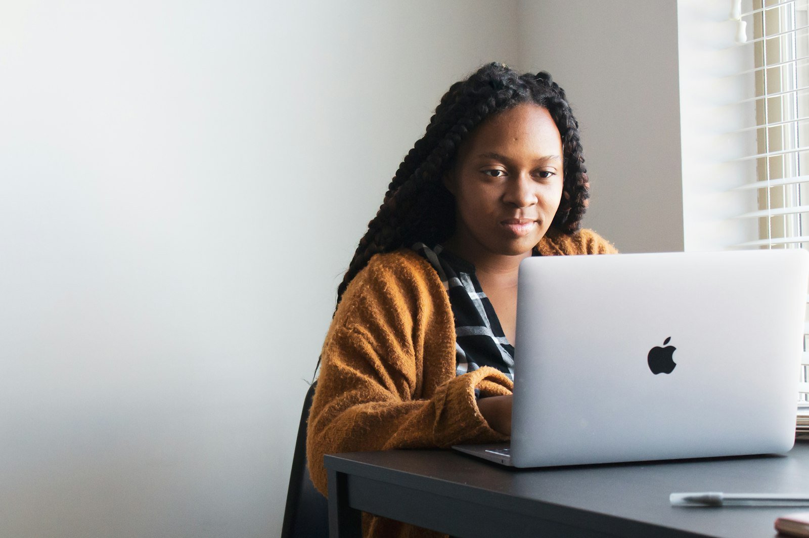 A student working on a laptop at a desk by a window.