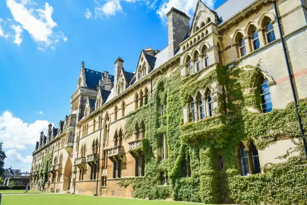 An ivy-covered Gothic university building under a bright blue sky.
