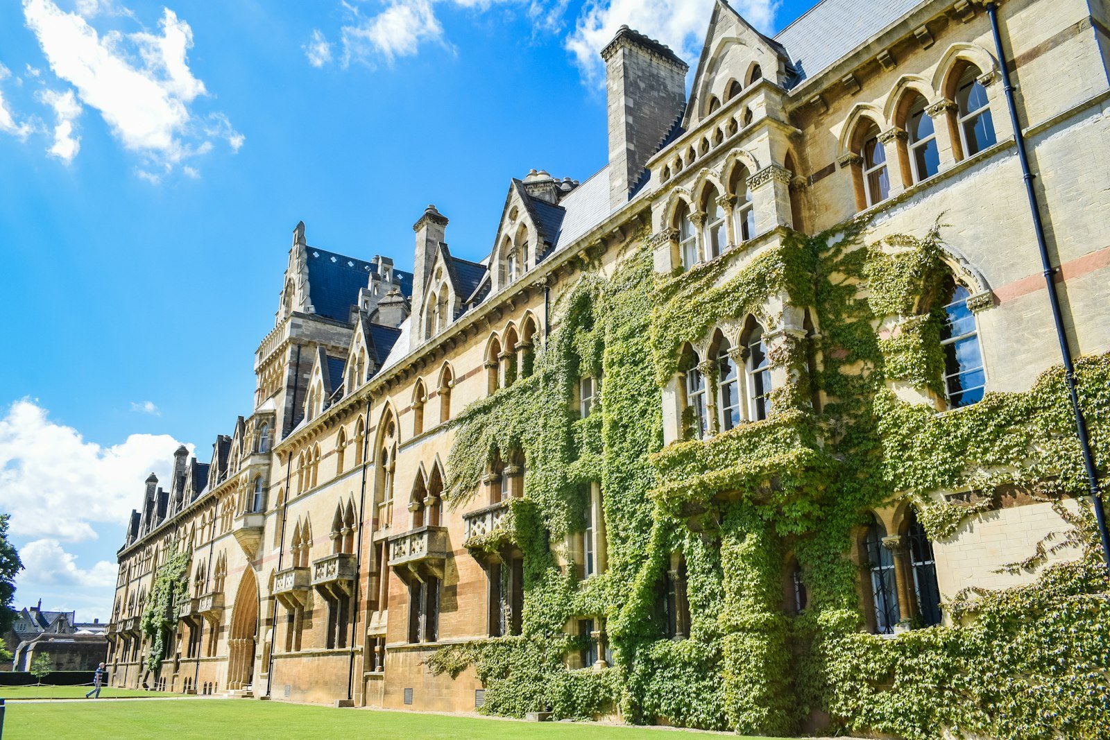 An ivy-covered Gothic university building under a bright blue sky.